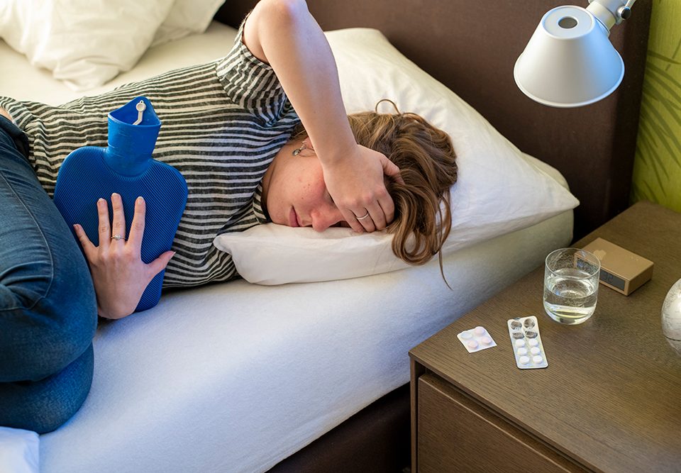 Mulher deitada na cama com dor de cabeça e corporal devido ao carnaval