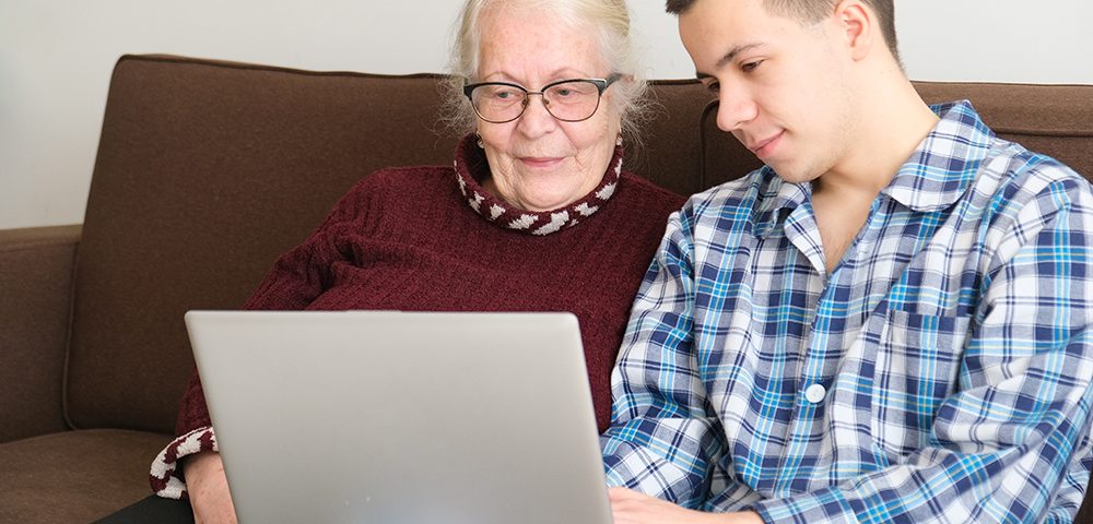 Jovem ensina uma mulher idosa a procurar informações no novo site da Med-Tour Saúde.