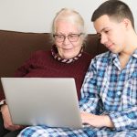 Jovem ensina uma mulher idosa a procurar informações no novo site da Med-Tour Saúde.