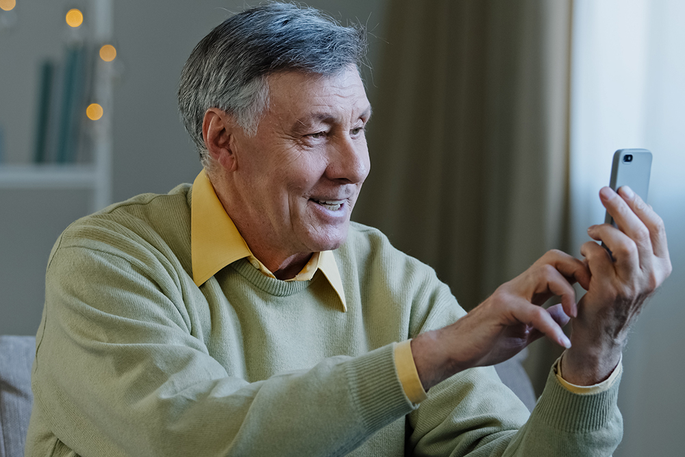 Homem segurando o celular e navegando no novo site da Med-Tour Saúde.