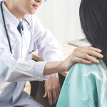 Médico amigável consolando uma paciente e usando a mão no ombro para ajudá-la a relaxar no consultório durante a recepção