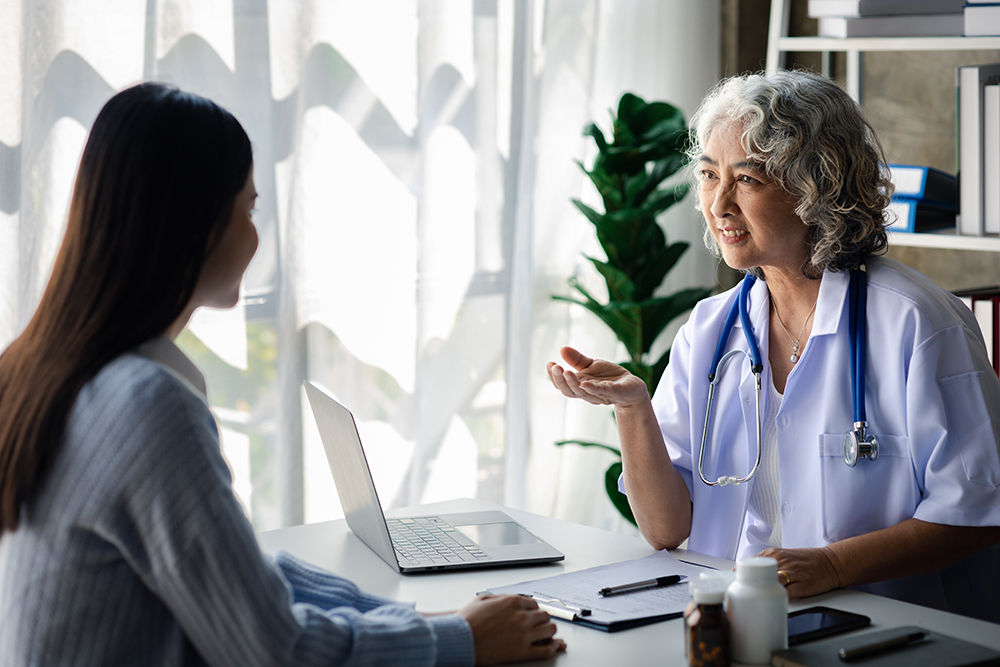 Médica idosa e paciente mulher sentadas na sala de consultas.