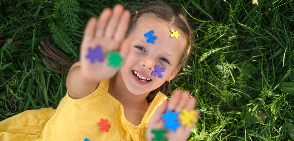 O rosto e as palmas das mãos estão cobertos por quebra-cabeças de papel colorido.