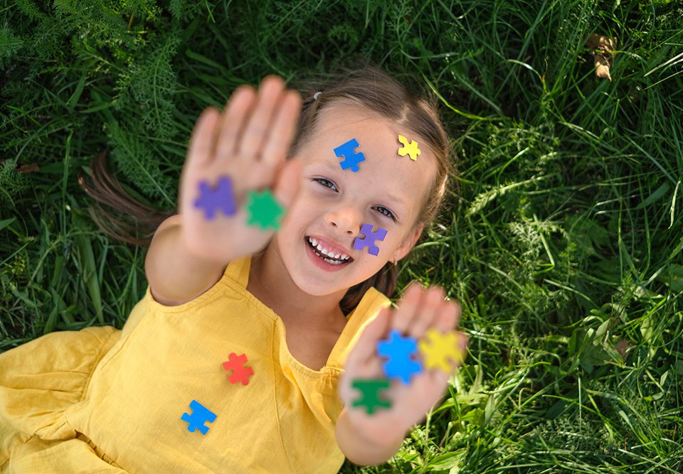 O rosto e as palmas das mãos estão cobertos por quebra-cabeças de papel colorido.