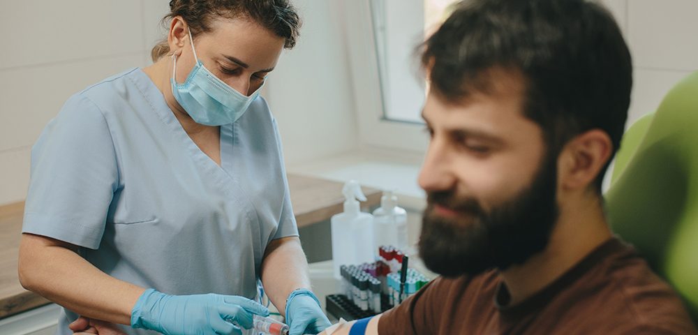 Profissional médico realizando procedimento de coleta de sangue no braço do paciente na clínica.